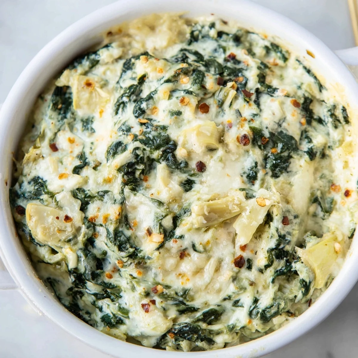 Warm Spinach and Artichoke Dip, bubbly and golden, ready to be scooped with crispy crackers.