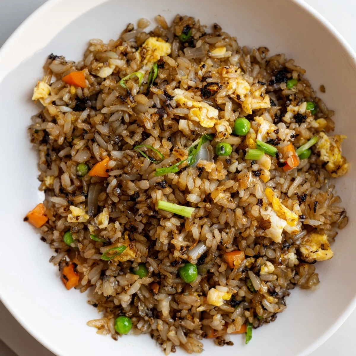 Black Garlic Fried Rice with glistening jasmine rice, fresh scallions, and vibrant mixed vegetables in a wok.  
