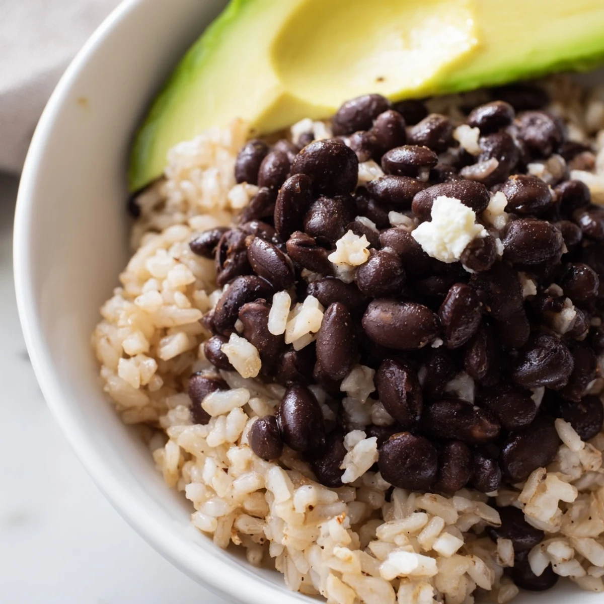 Hearty vegetarian Brown Rice Burrito Bowl featuring warm seasoned beans, crisp corn, fresh cherry tomatoes, and diced red and yellow peppers, garnished with cilantro and served with lime wedges for a zesty finish.  