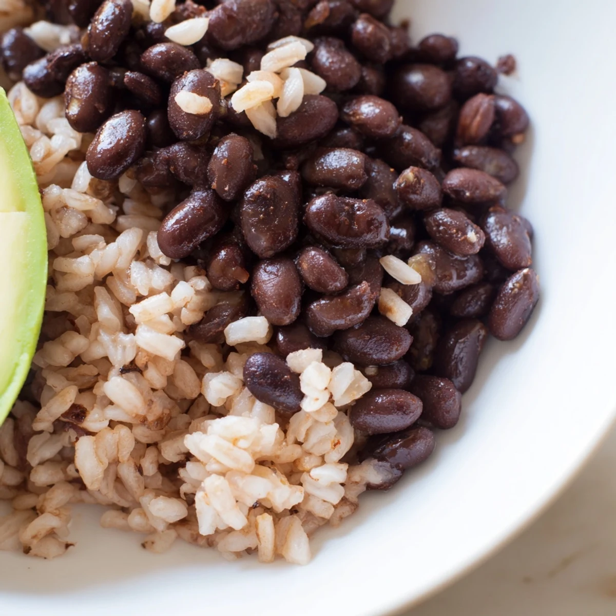 Satisfying gluten-free Brown Rice Burrito Bowl assembly with tender brown rice, hearty black beans, sautéed vegetables, sliced avocado, cheese, and sour cream, arranged neatly in a rustic bowl for a wholesome meal.