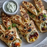 Easter bunny-shaped quesadillas filled with melted cheese, bell peppers, and sweet corn, decorated with olives and carrots for a festive snack.