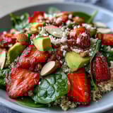 Fresh strawberry avocado quinoa salad with creamy avocado and juicy berries in a bright citrus dressing.  