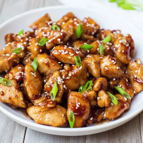 Golden, glazed Sweet and Spicy Sriracha Honey Chicken glistening after it's tossed in the zesty, sweet sauce.