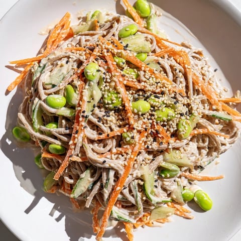 A close-up of vibrant Asian Sesame Noodle Salad, coated in creamy dressing and sprinkled with sesame seeds.
