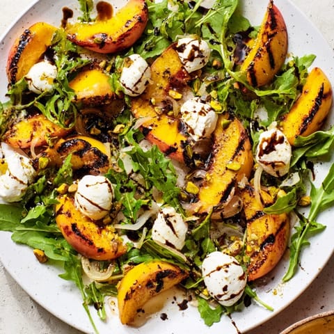 Fresh Grilled Peach Salad featuring arugula and burrata, perfect for a summer lunch or dinner.
