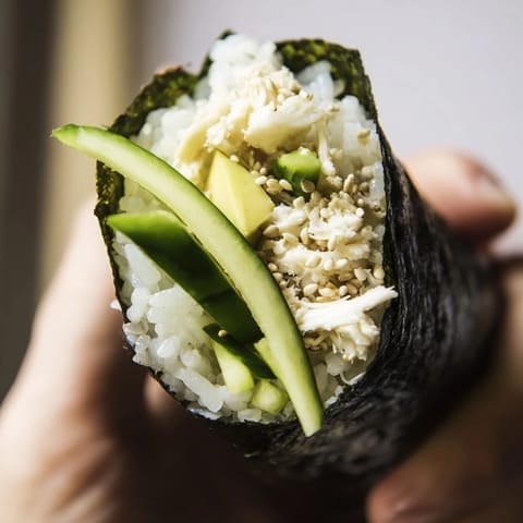 Delicate sushi rice hand rolls feature creamy avocado, sweet crab, and crunchy cucumber wrapped in a crisp nori sheet.  