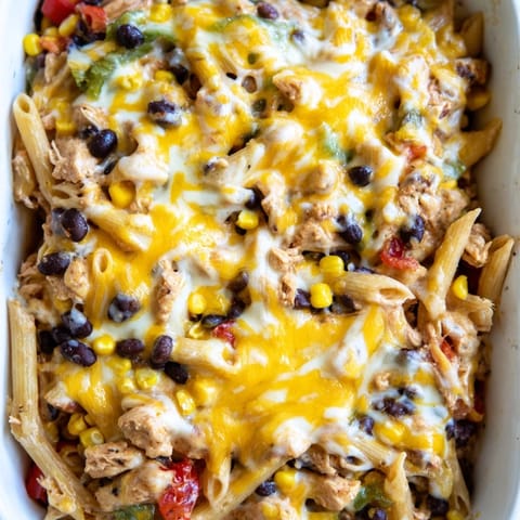 Freshly baked Chicken Burrito Pasta with black beans, corn, and cheddar cheese bubbling in the dish.