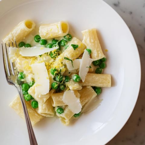 Close-up of Pea & Lemon Ricotta Pasta twirled on a fork, showcasing the velvety ricotta sauce and tender spring peas.  