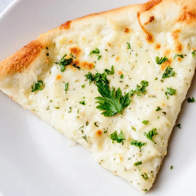 Overhead view of Creamy Garlic White Pizza with melted cheese, garlic cream sauce, and a perfectly golden, crispy edge.
