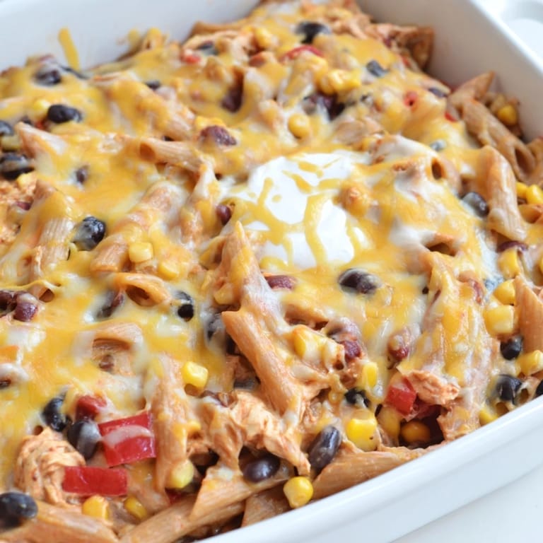 A hearty slice of Chicken Burrito Pasta served with a lime wedge and sour cream garnish.